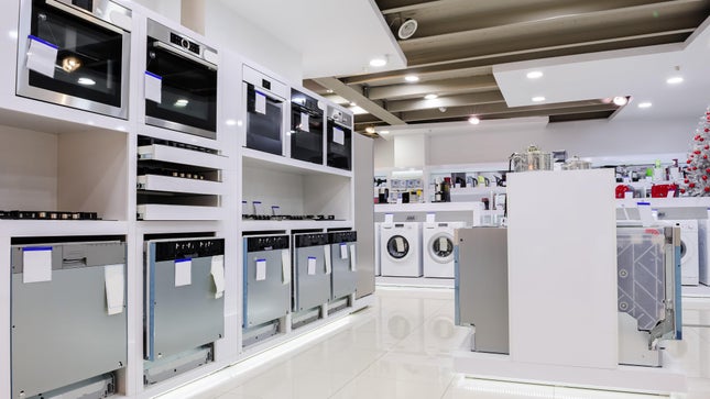 Dentro de una tienda de electrodomésticos se exhiben estufas, microondas y lavadoras.